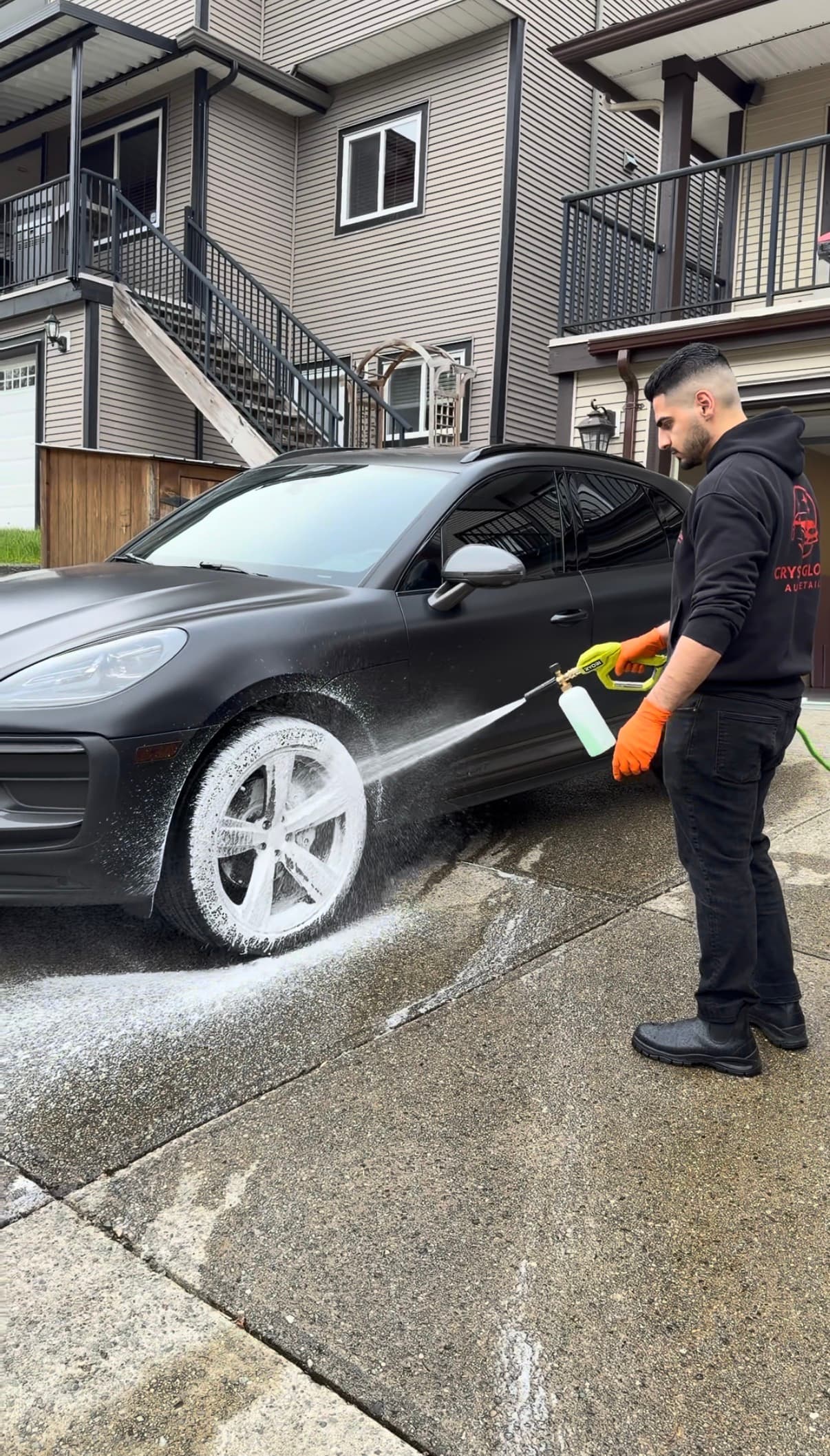 Crystal Gloss owner foam-washing a black Porsche by hand in Vancouver